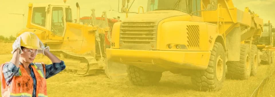 A worker in a hard hat in front of heavy highway equipment
