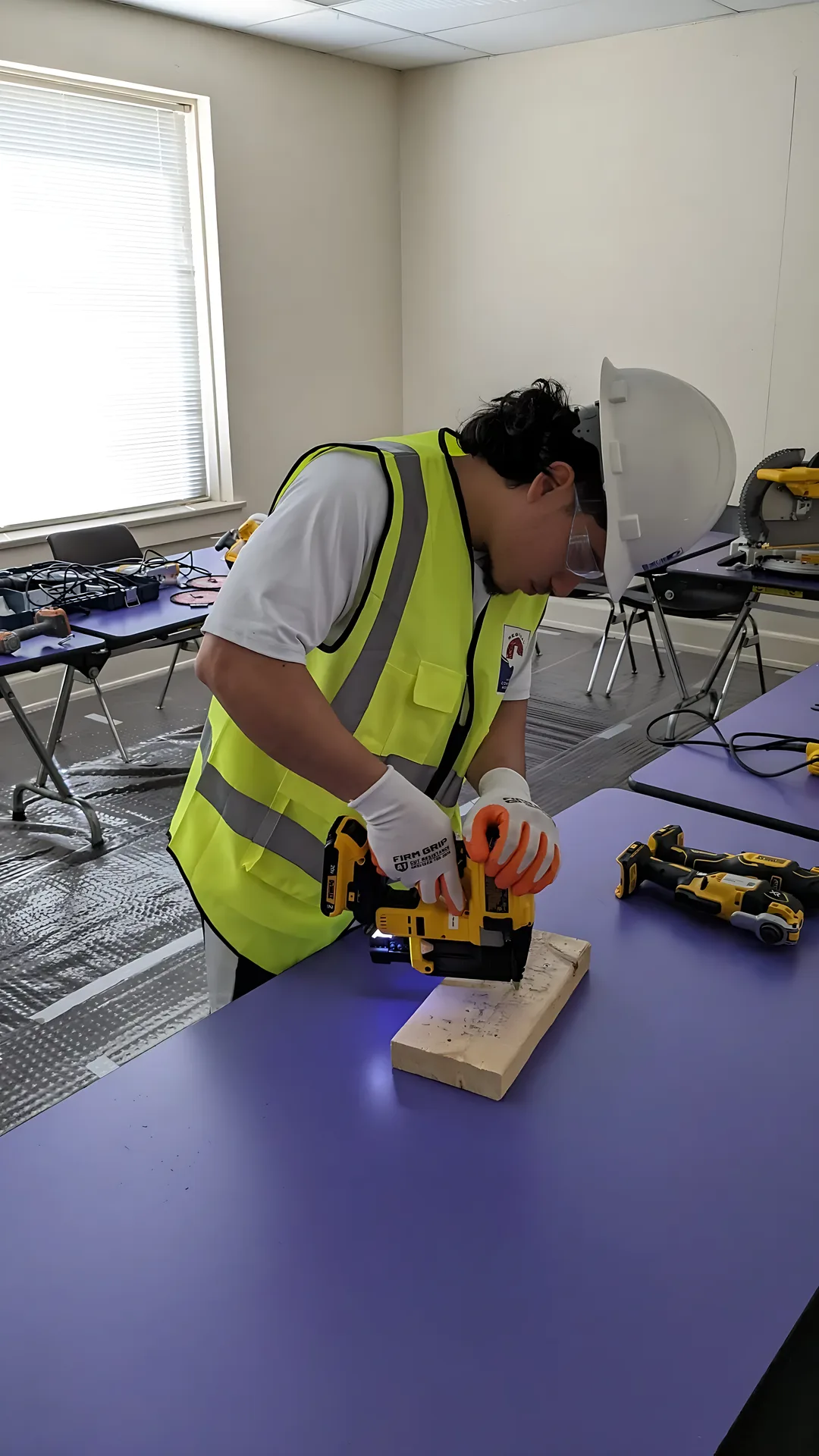 A participant uses a power tool on a wooden block during construction training.